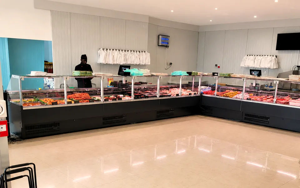 L’intérieur de la boucherie : les vitrines réfrigérées le long du comptoir